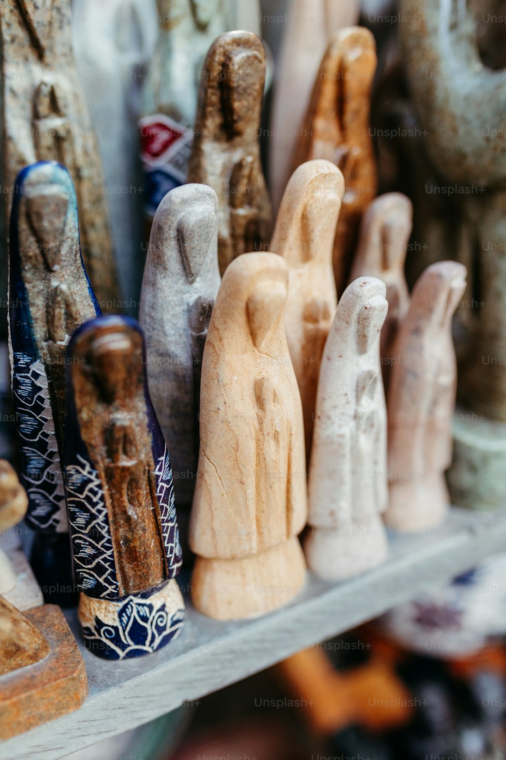 uma prateleira cheia de estatuetas de madeira de diferentes formas e tamanhos