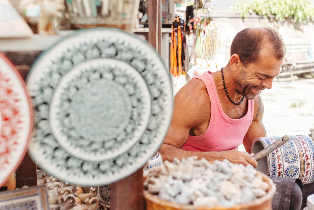 a man in a pink tank top working on pottery