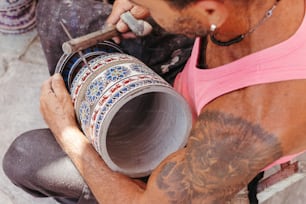 Un uomo con tatuaggi sul braccio che tiene una tazza