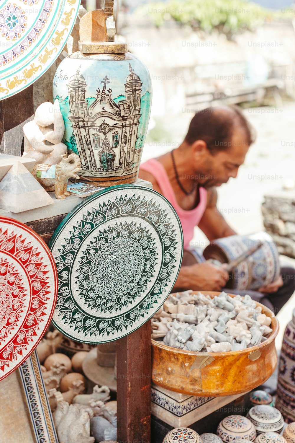 um homem sentado em frente a uma exposição de cerâmica