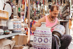 a man working on a vase in a market