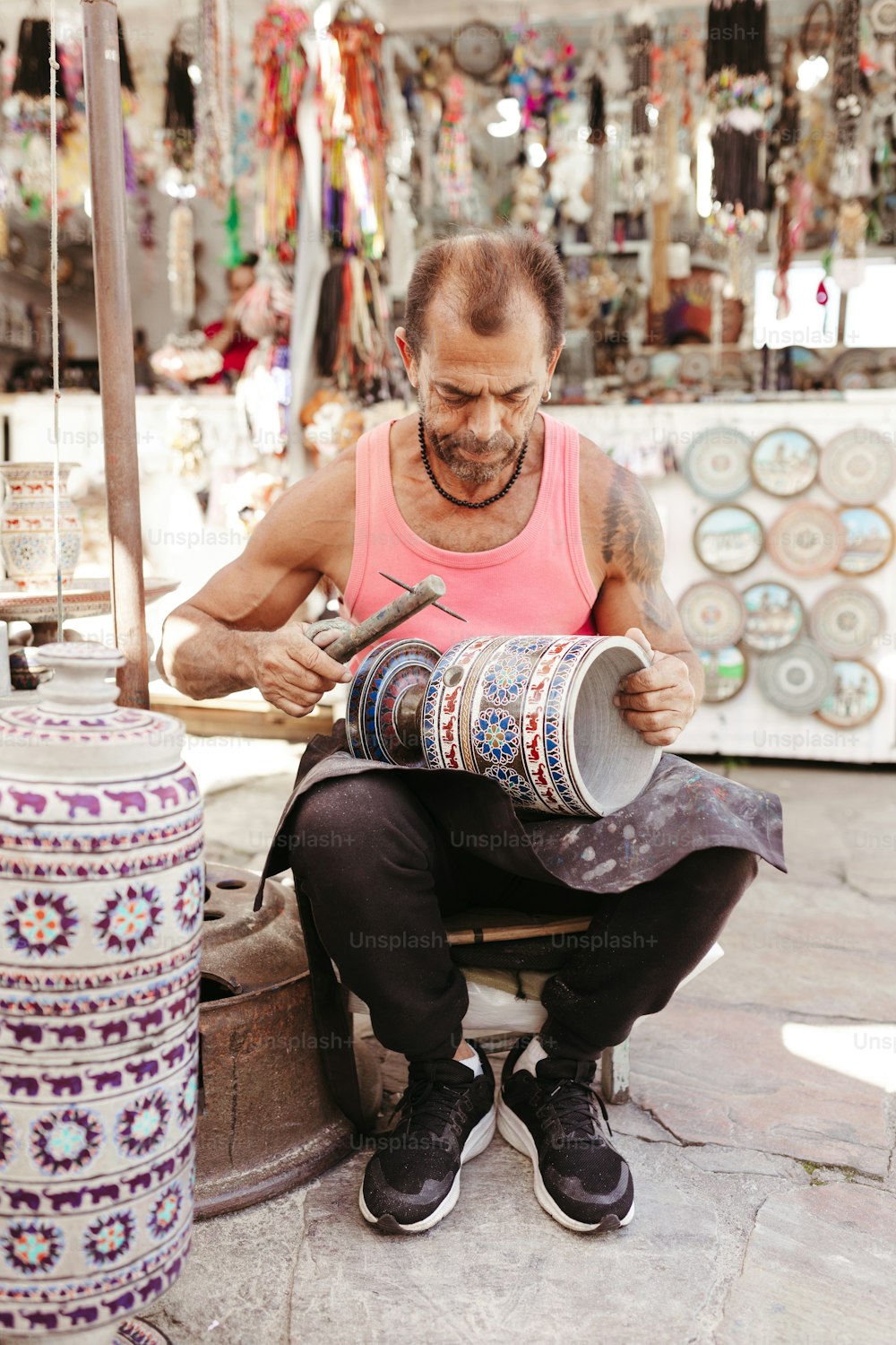 un uomo seduto su uno sgabello che lavora su un pezzo di stoffa