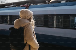 a woman with a backpack standing in front of a train