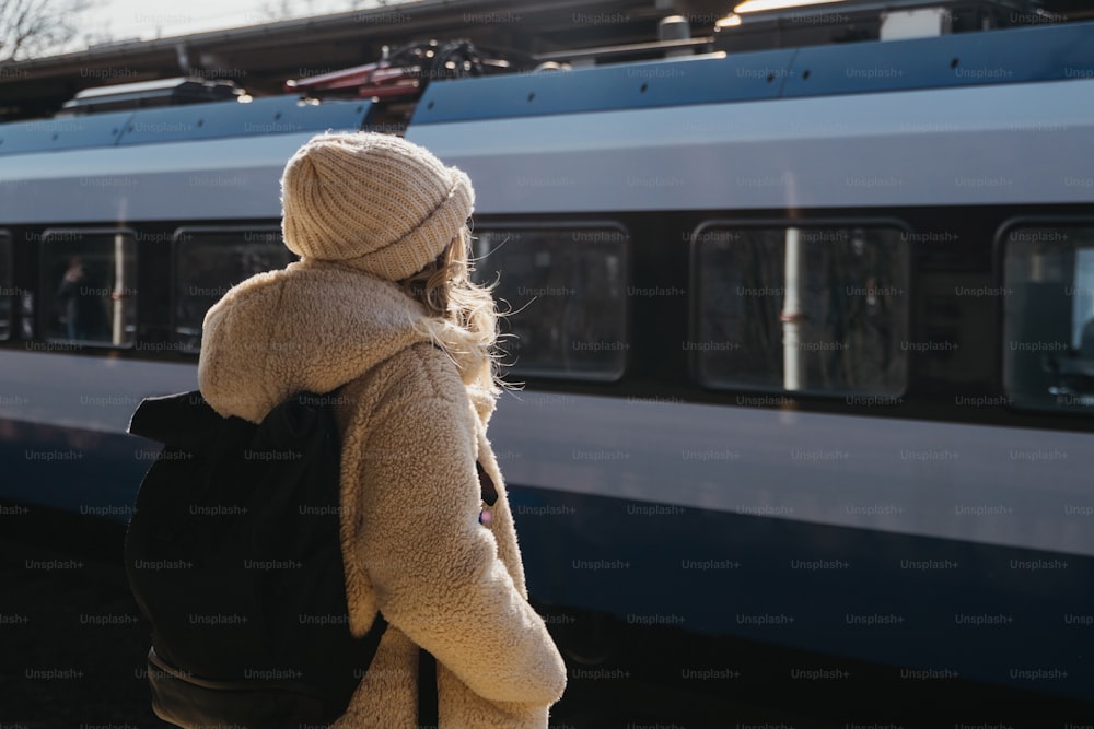 a woman with a backpack standing in front of a train