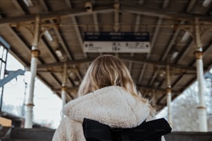 a woman in a white coat is waiting for a train