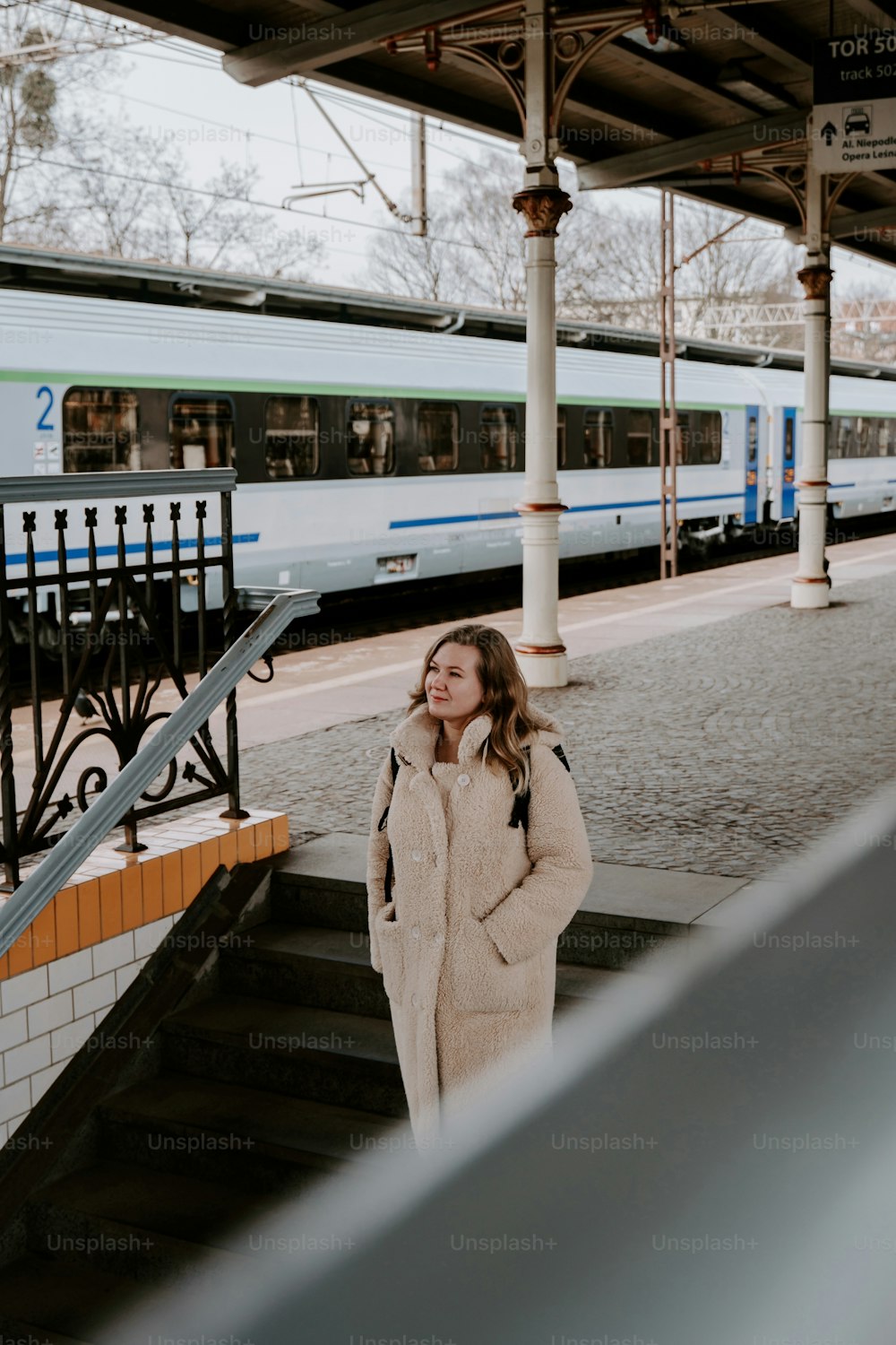 a woman is standing on the steps of a train station