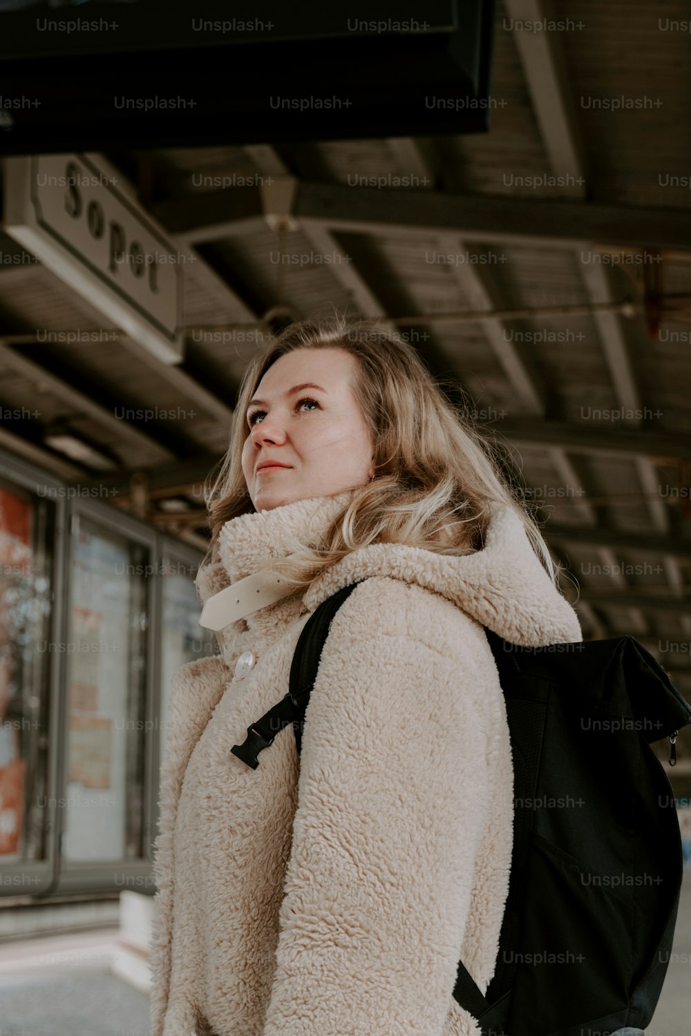 Una donna con uno zaino in piedi davanti a una stazione ferroviaria