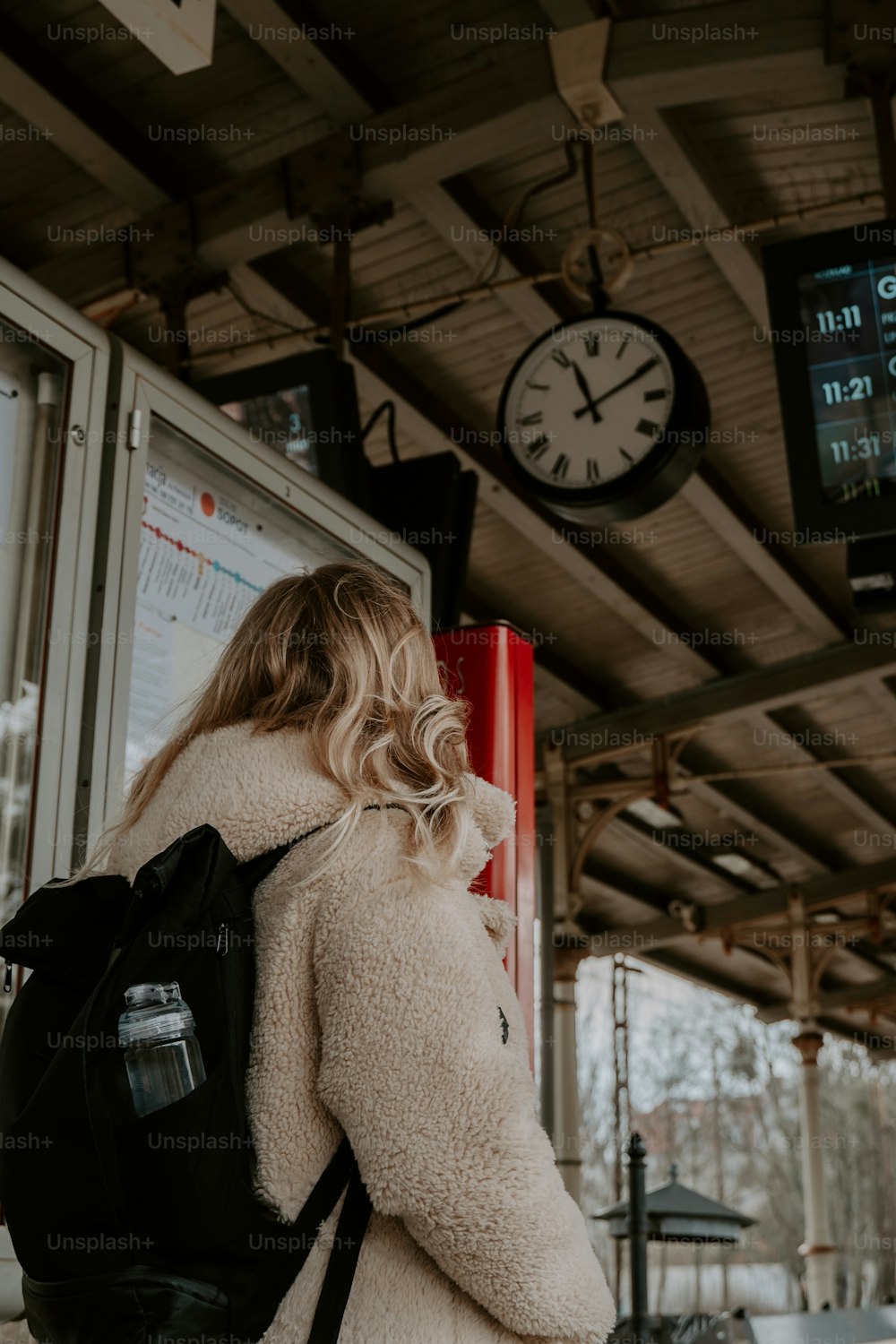 uma mulher com uma mochila está esperando por um trem