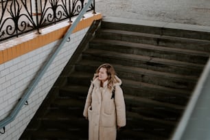 a woman in a coat is standing on a set of stairs