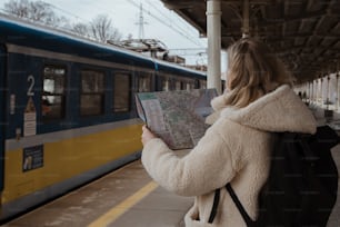 Una mujer está mirando un mapa en una estación de tren