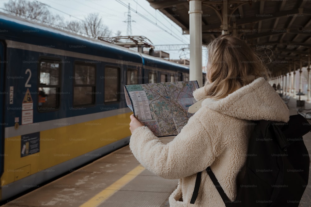 a woman is looking at a map at a train station