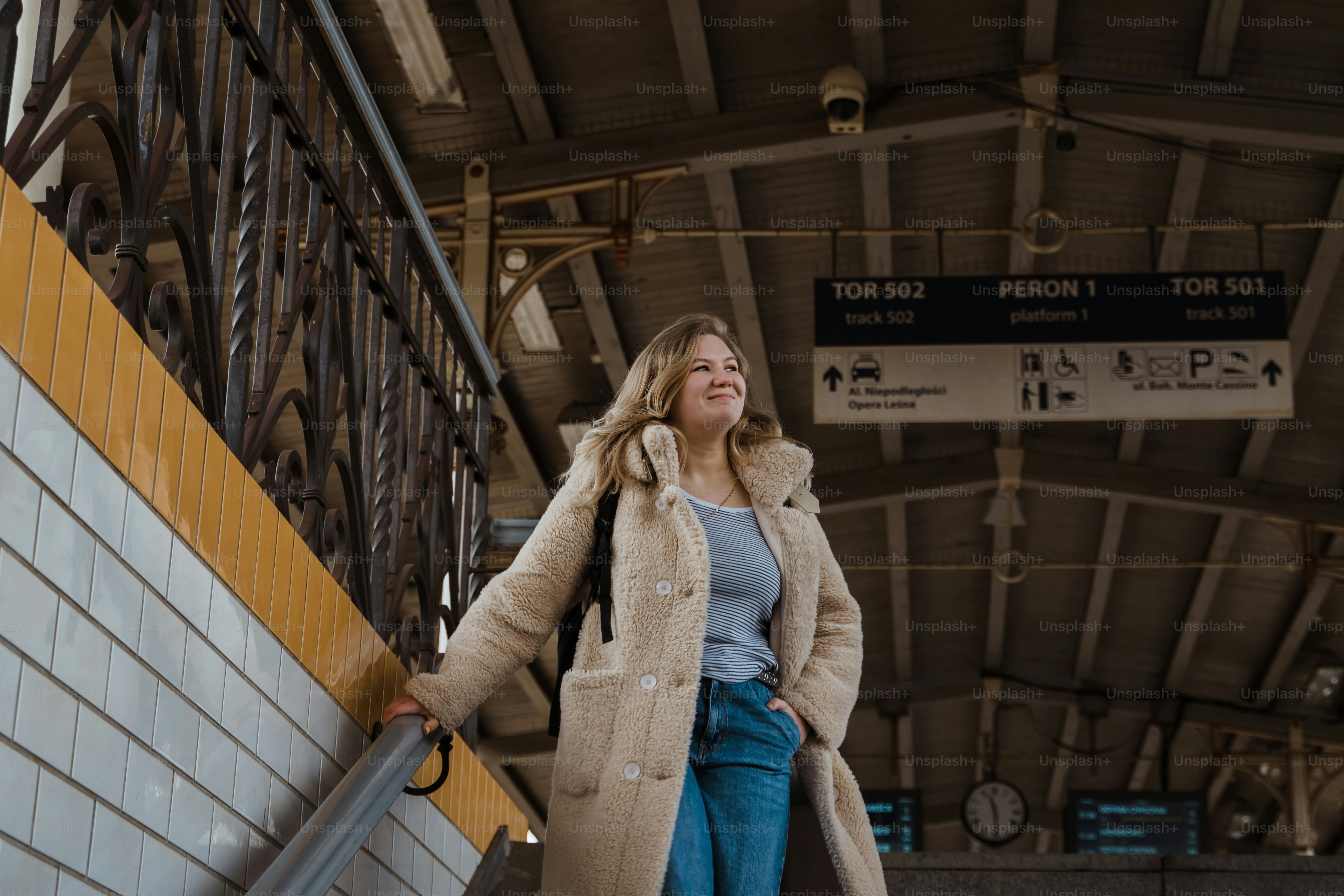 Eine Frau in Mantel und Jeans geht eine Treppe hinauf
