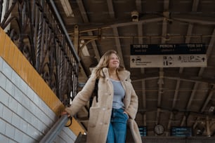 a woman in a coat and jeans is walking up a set of stairs