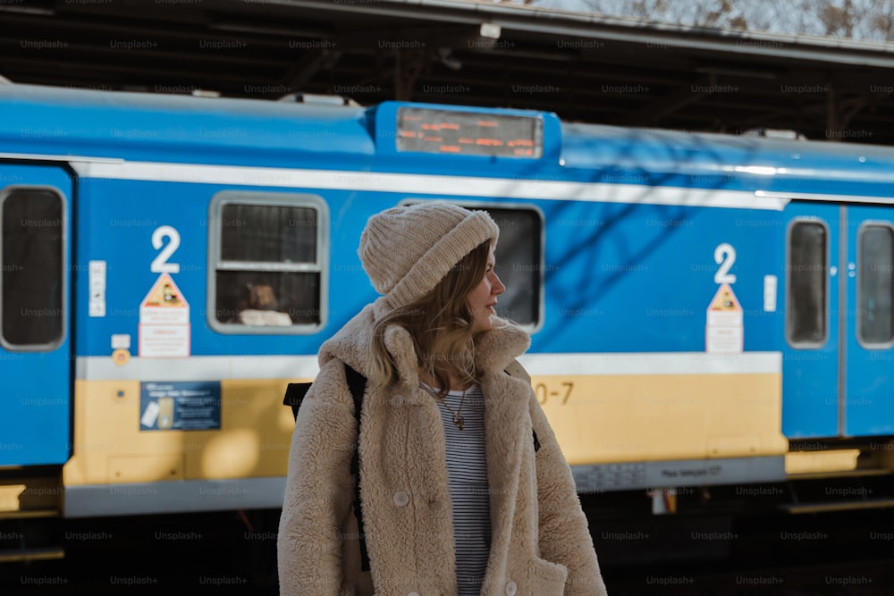 a woman standing in front of a blue train