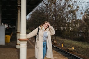 uma mulher em pé em uma plataforma de trem ao lado de um trem