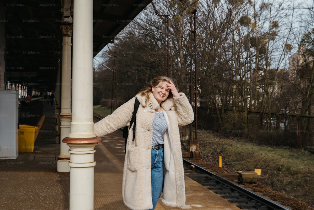 a woman standing on a train platform next to a train