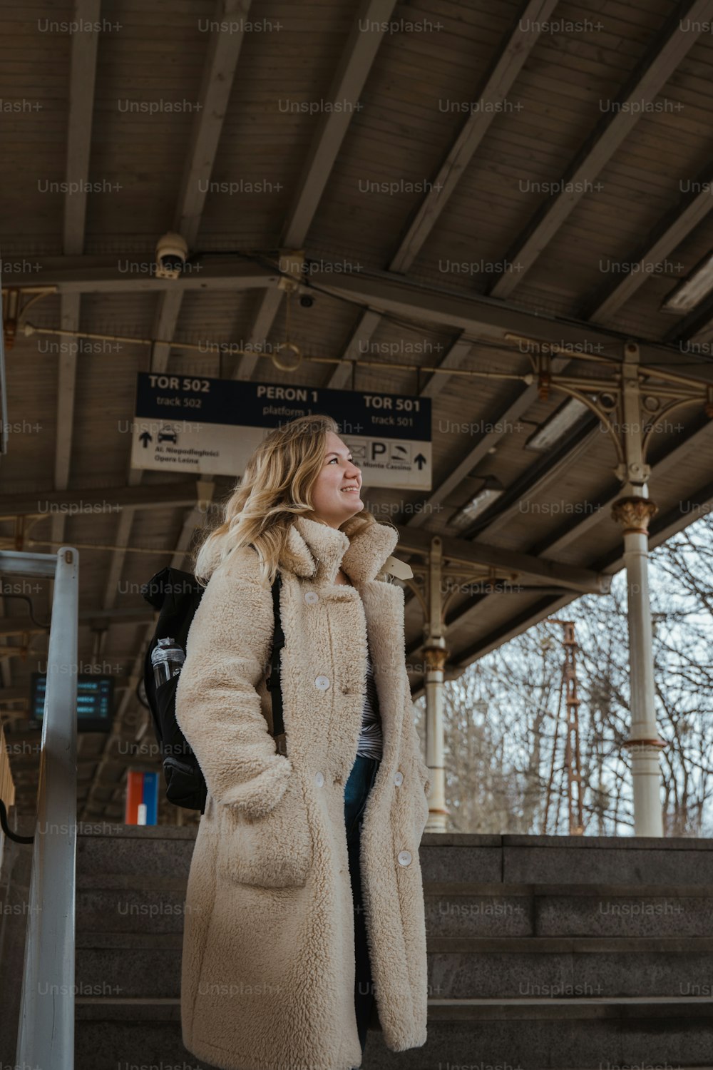 Une femme en long manteau debout sur une plate-forme