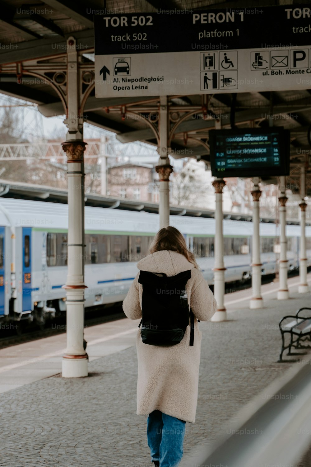 a woman walking towards a train at a train station