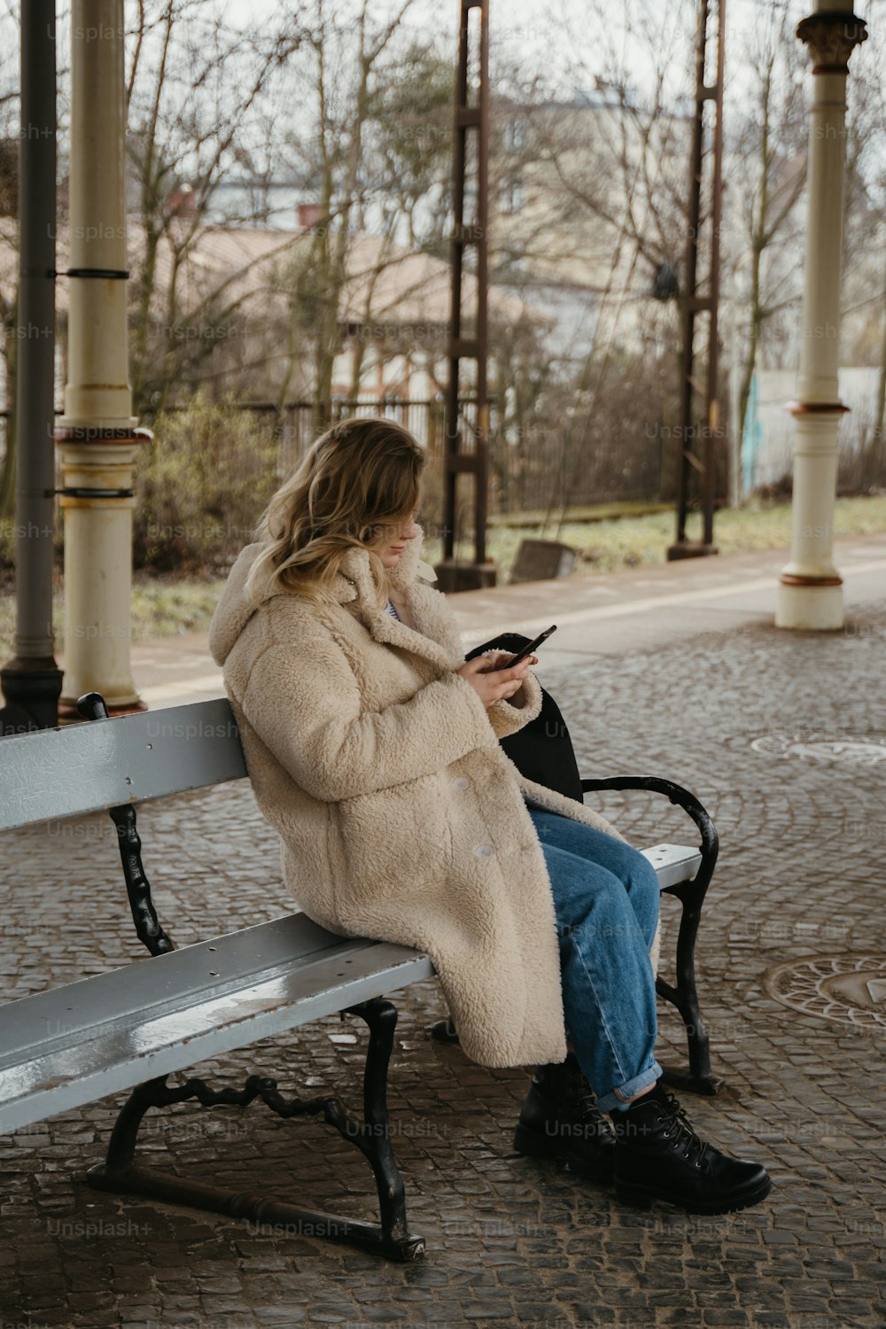 une femme assise sur un banc utilisant un téléphone cellulaire