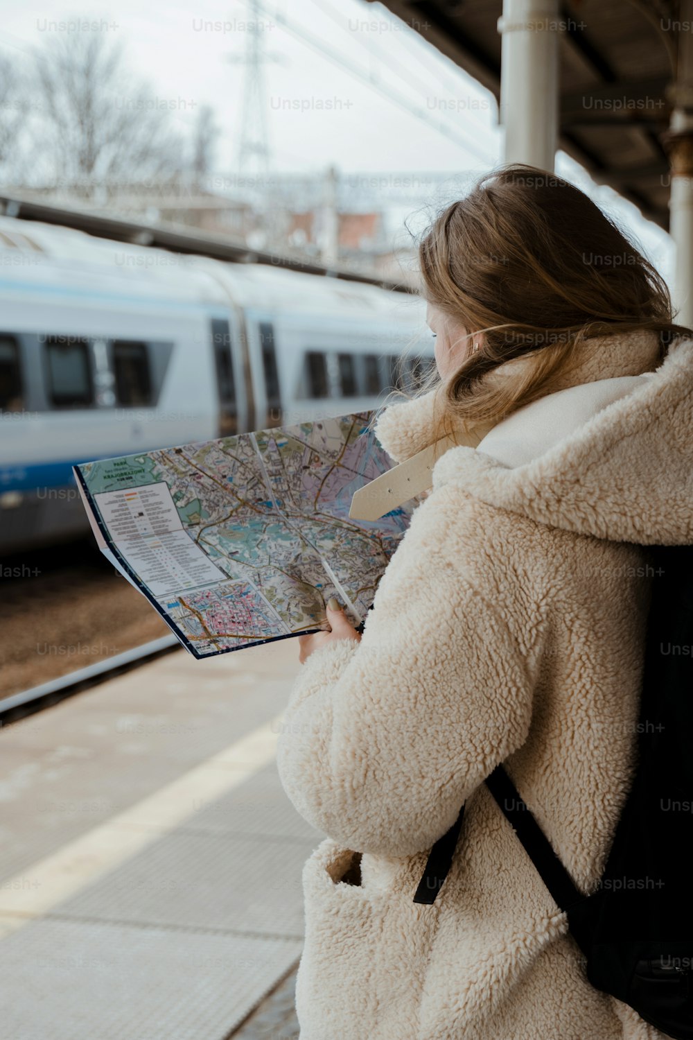 a woman is looking at a map while waiting for a train