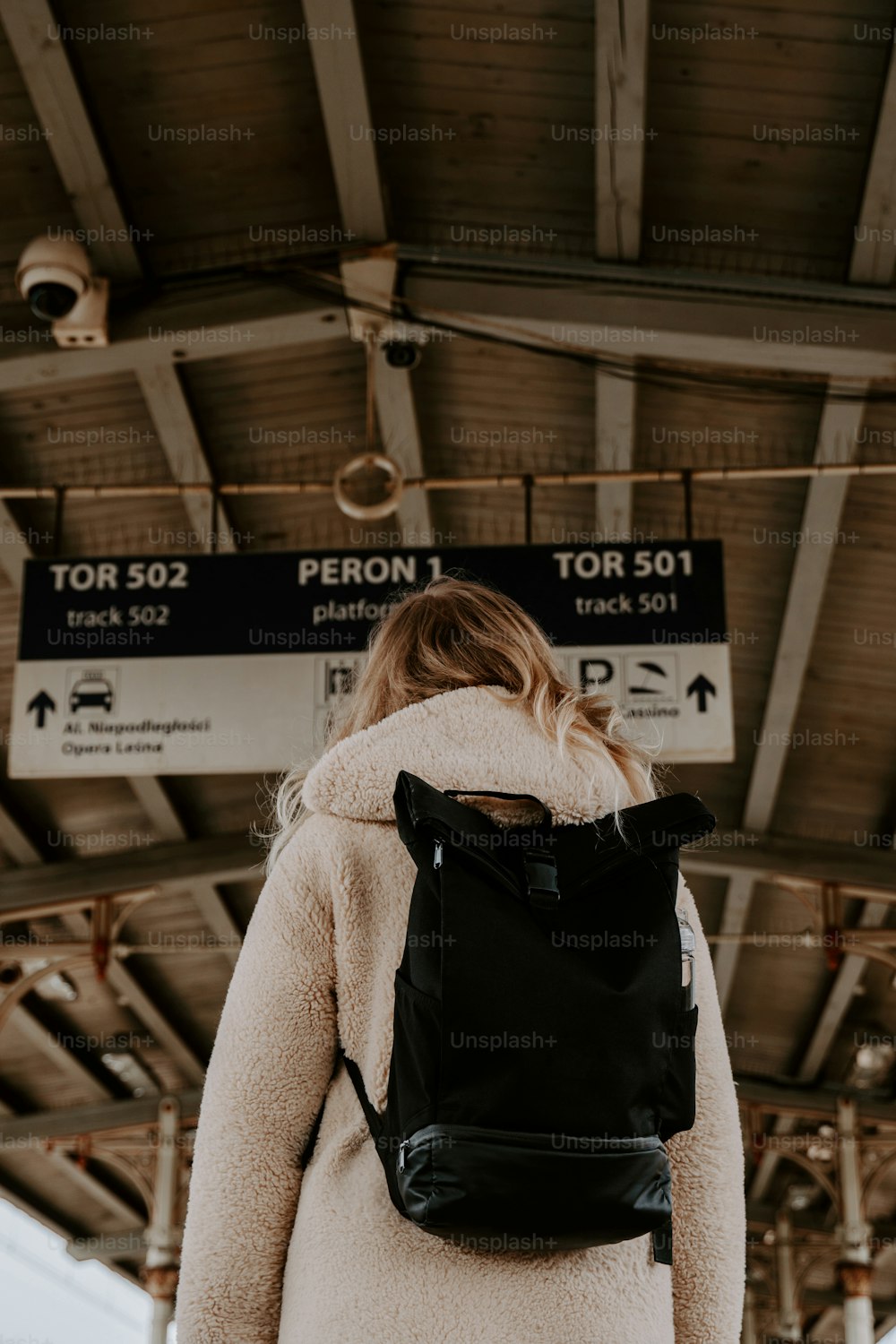 a woman with a black backpack standing in front of a train station