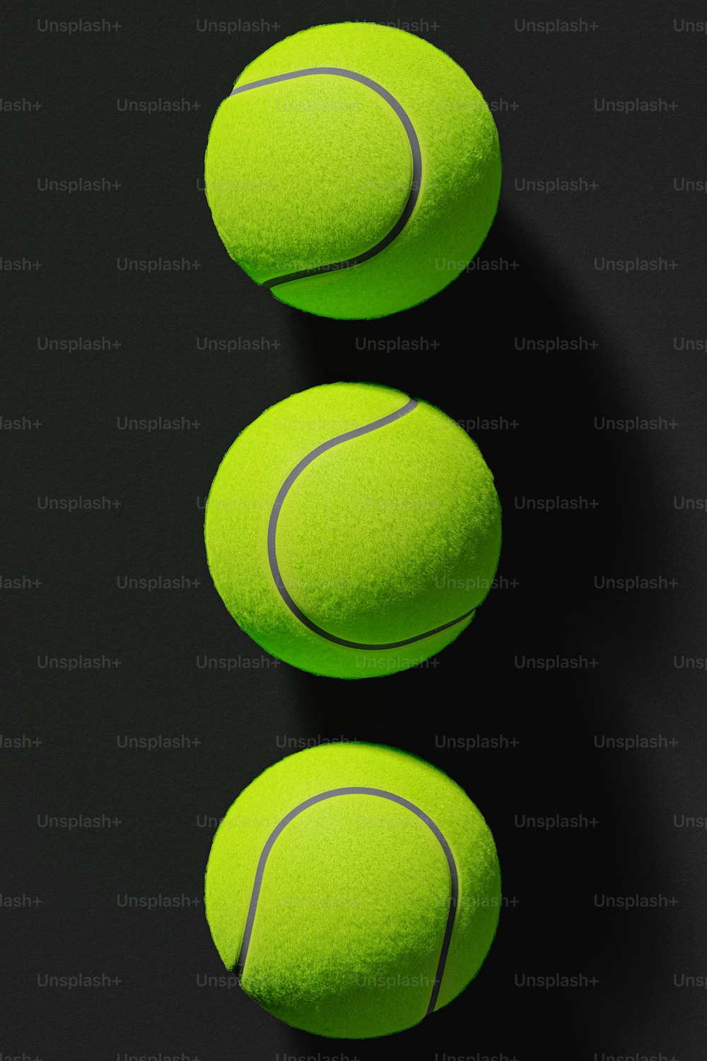 three tennis balls sitting on top of a black surface