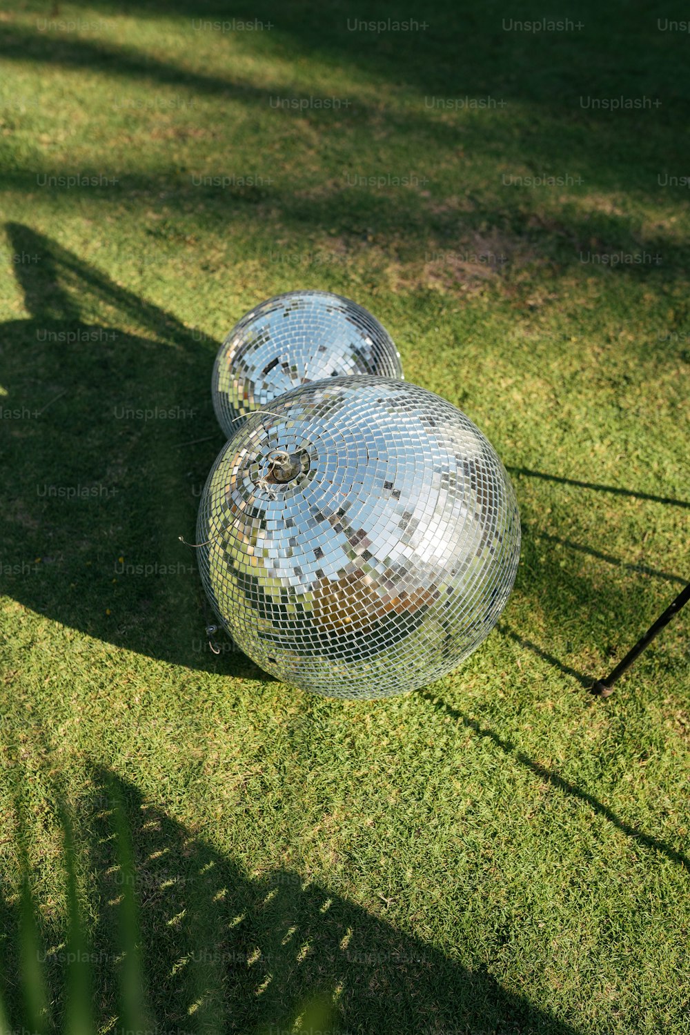 two disco balls sitting on top of a lush green field