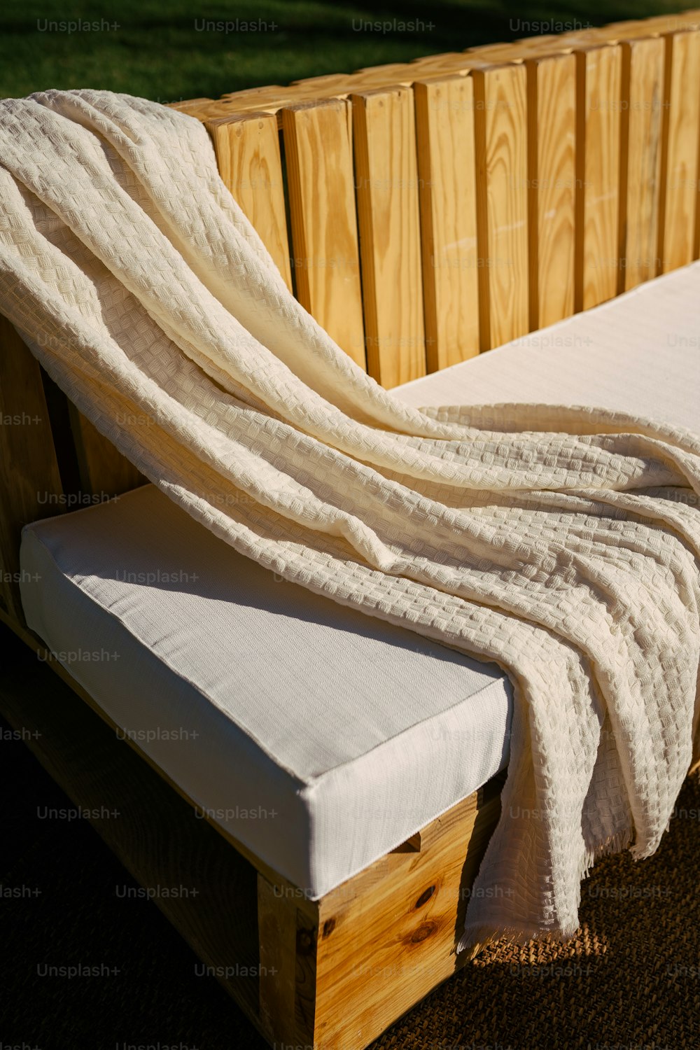 una coperta bianca seduta sopra una panca di legno