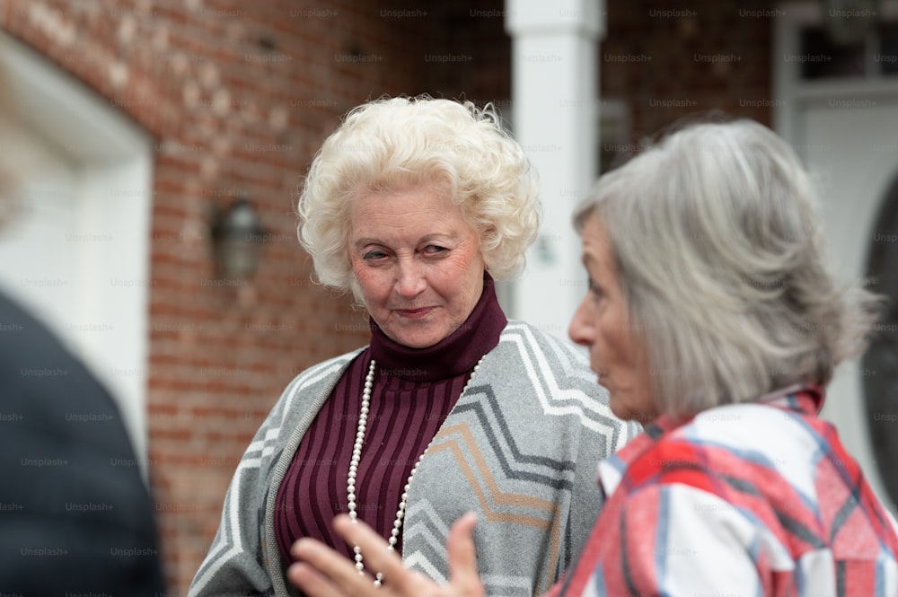 a woman talking to another woman in front of a brick building