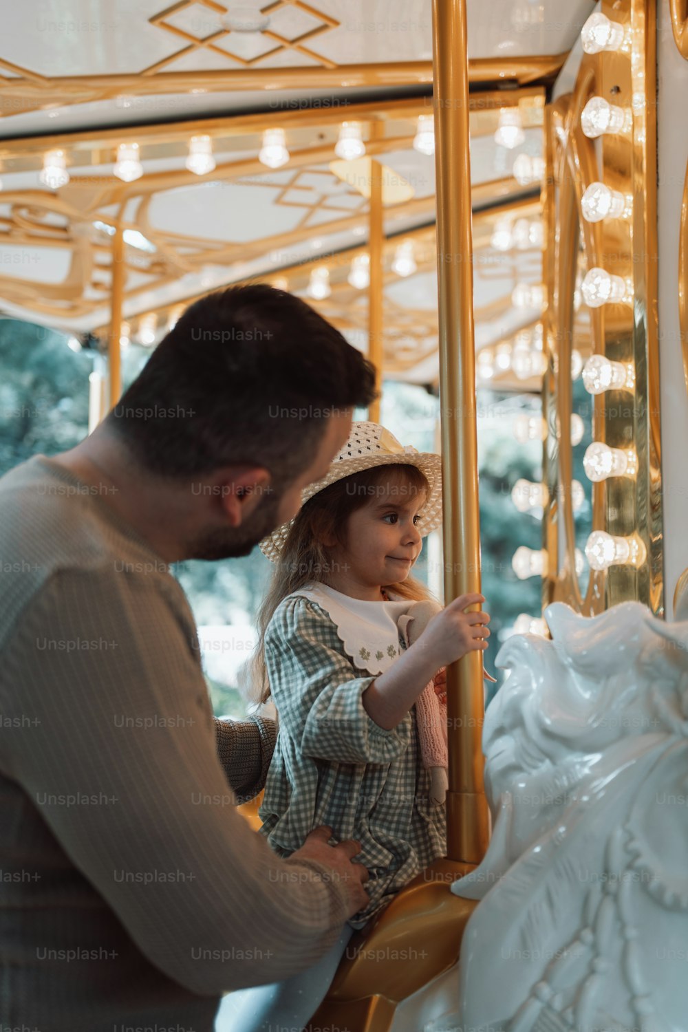 a man and a little girl standing in front of a carousel