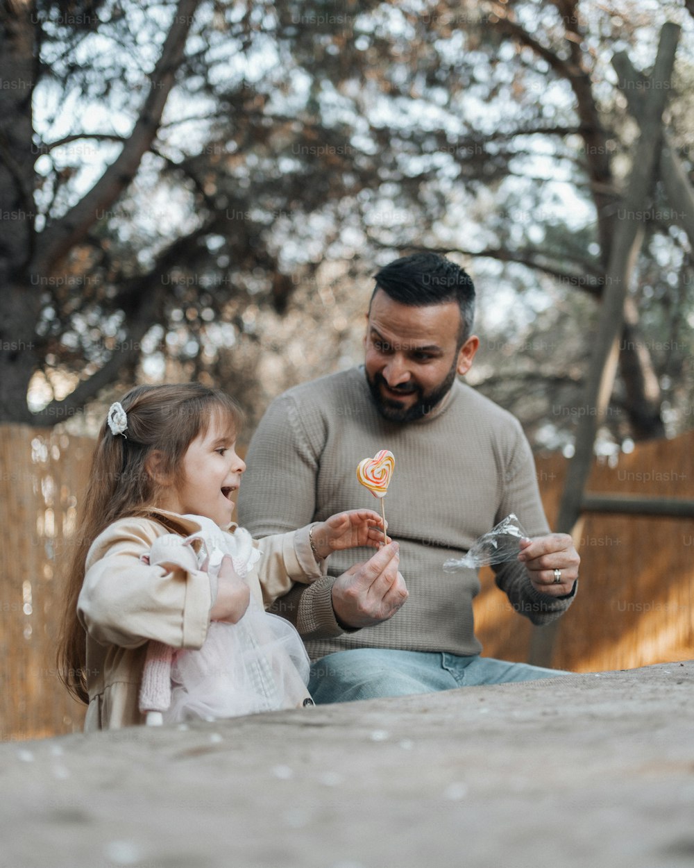 a man sitting next to a little girl holding a piece of pizza