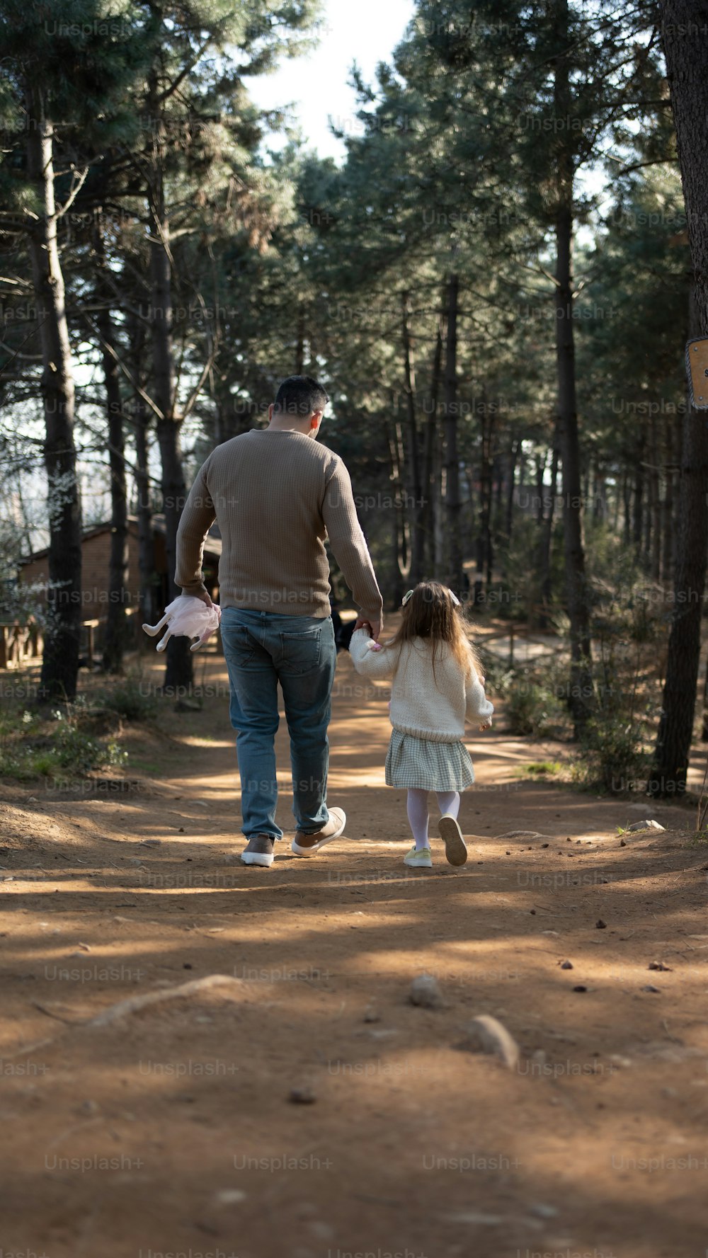 a man and a little girl walking down a dirt road