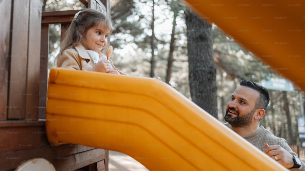 a man and a little girl playing on a slide