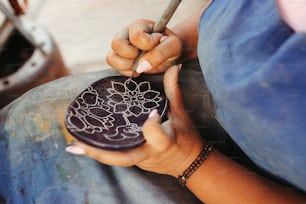 a woman is holding a small plate with a flower design on it