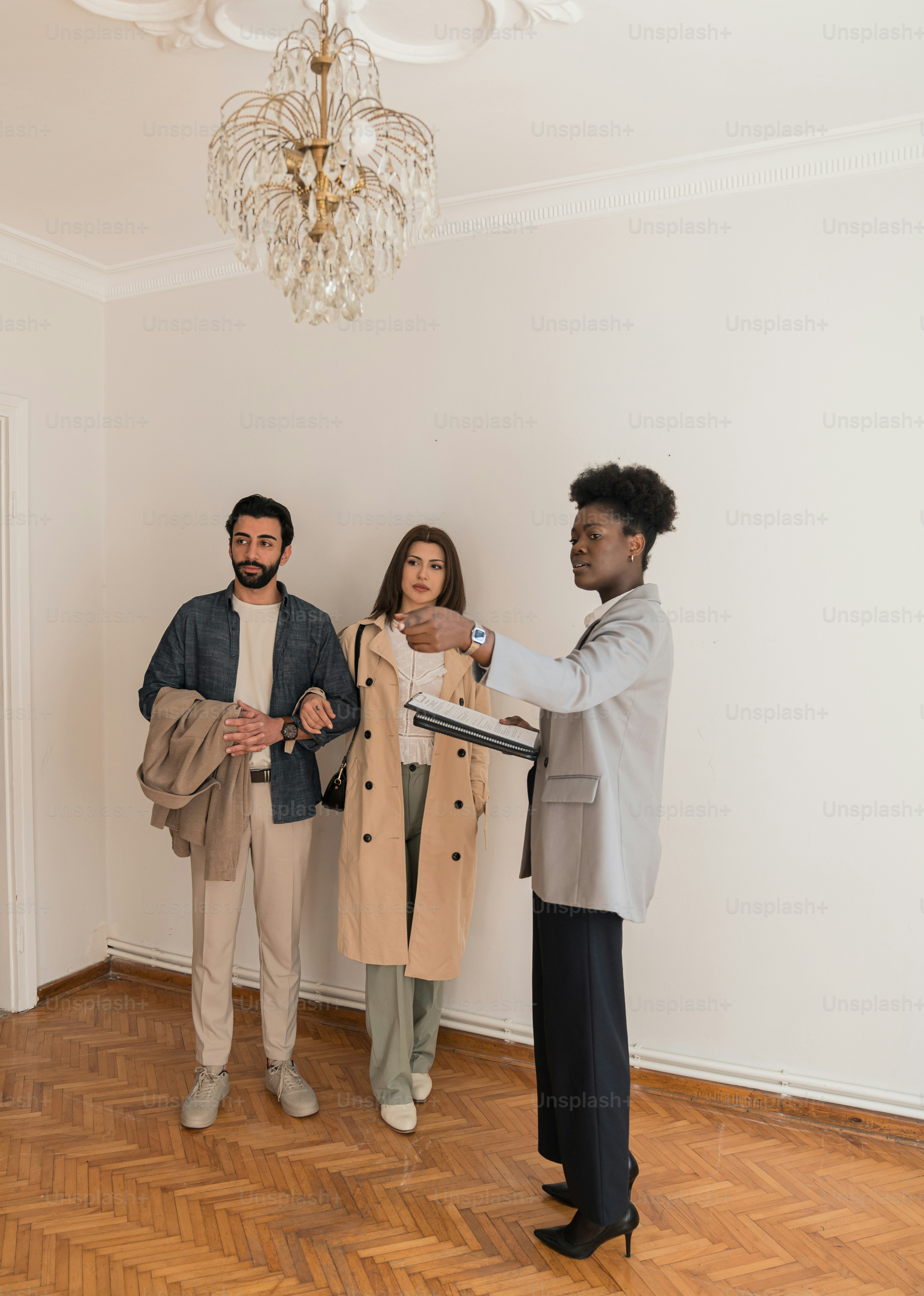 three people standing in a room with a chandelier