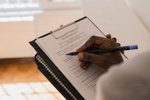 a person writing on a clipboard with a pen