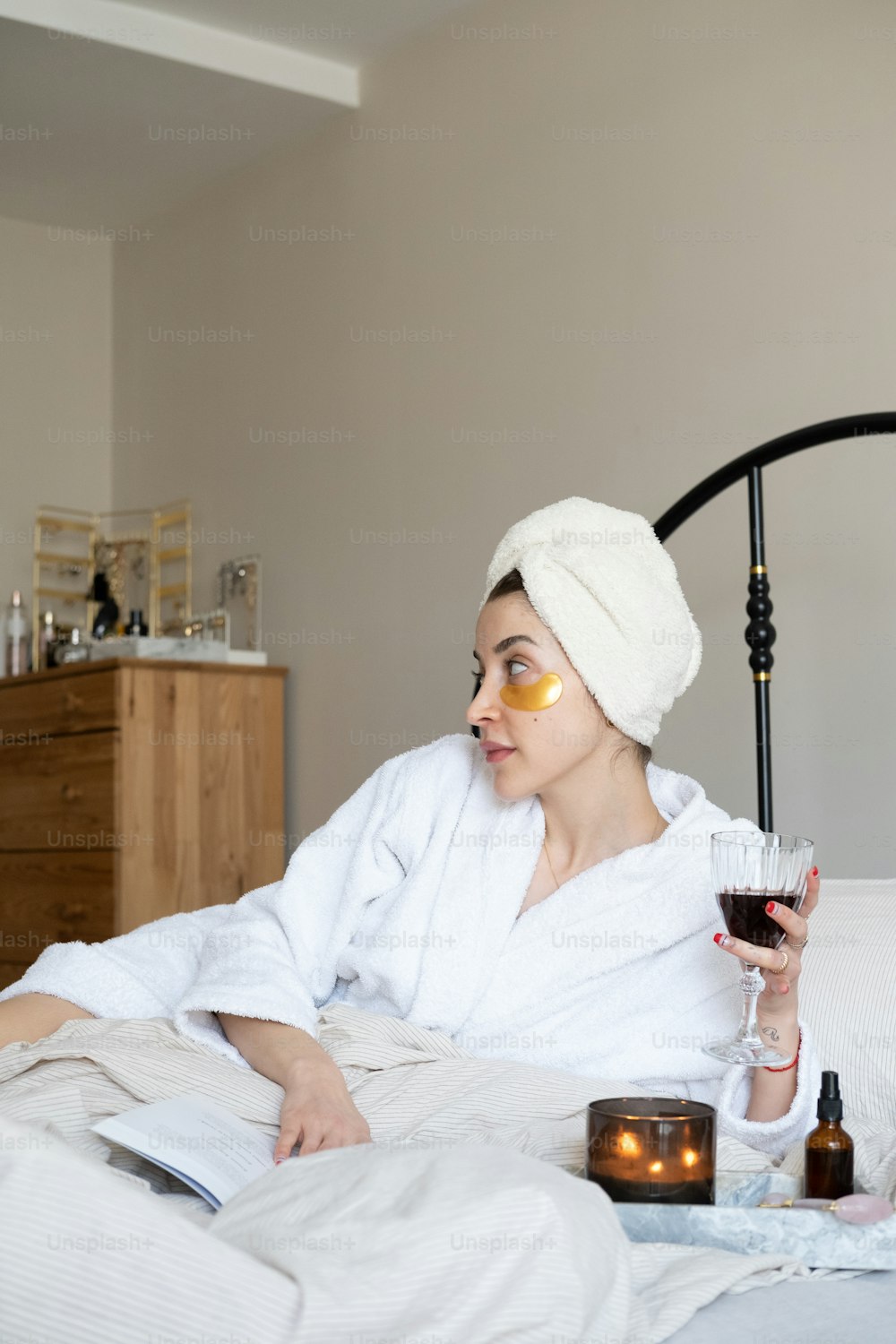eine Frau im Bademantel mit einem Glas Wein in der Hand