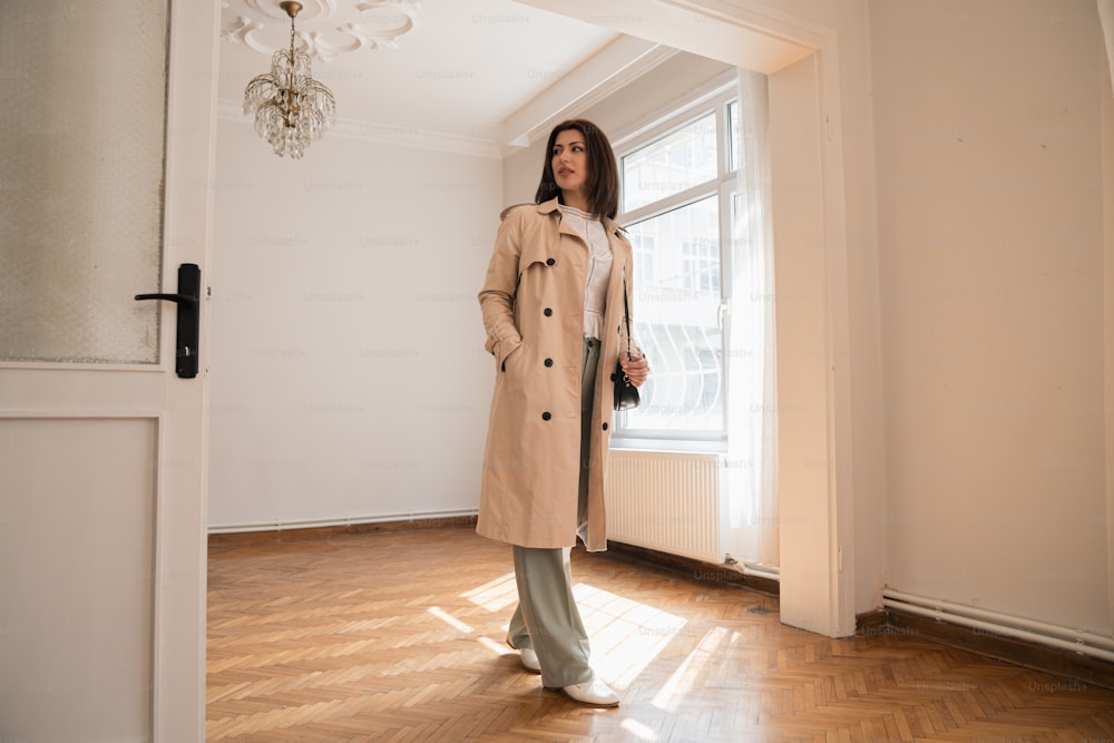 a woman standing in a room with a coat on