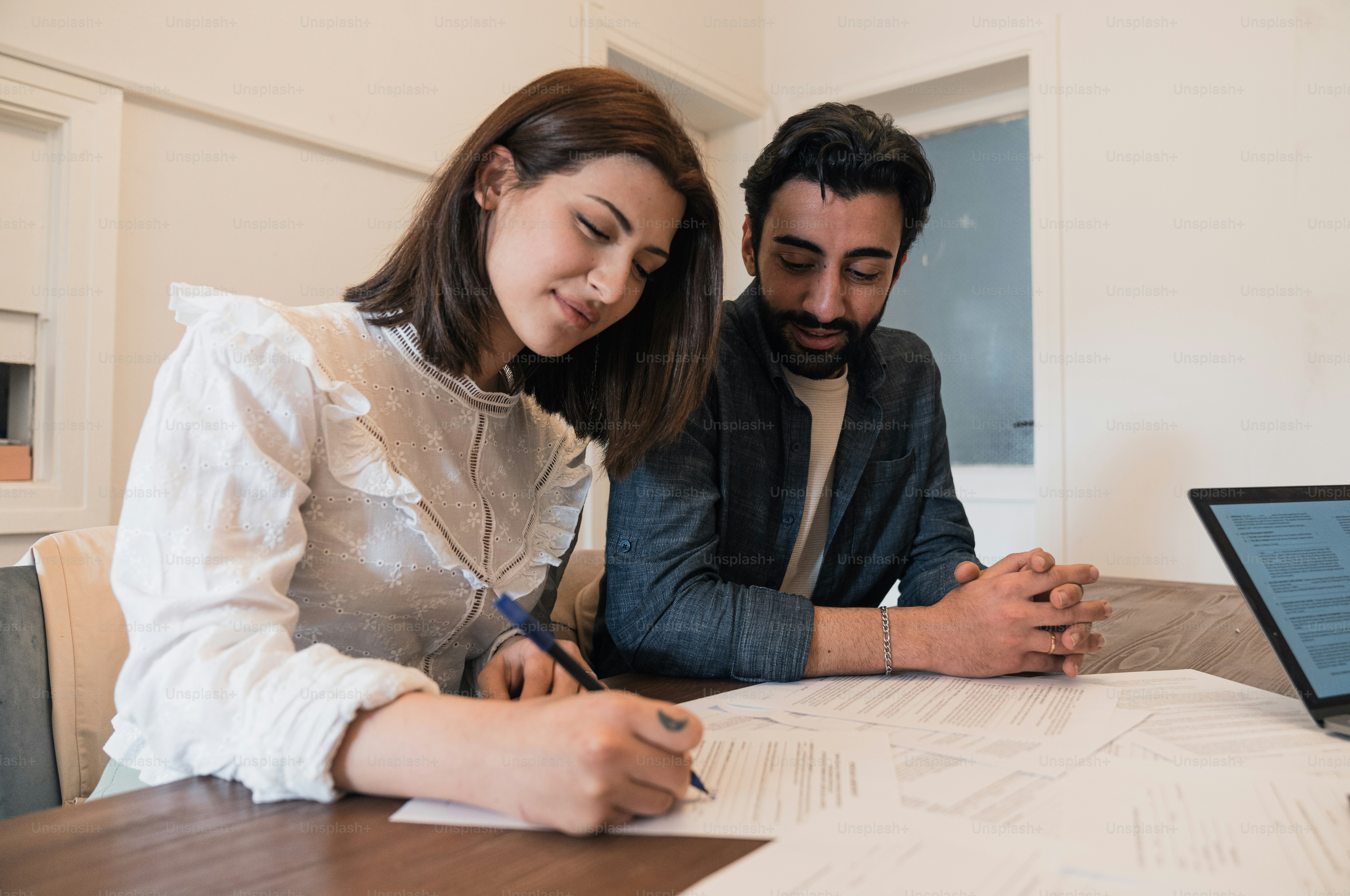 a man and a woman sitting at a table with a laptop