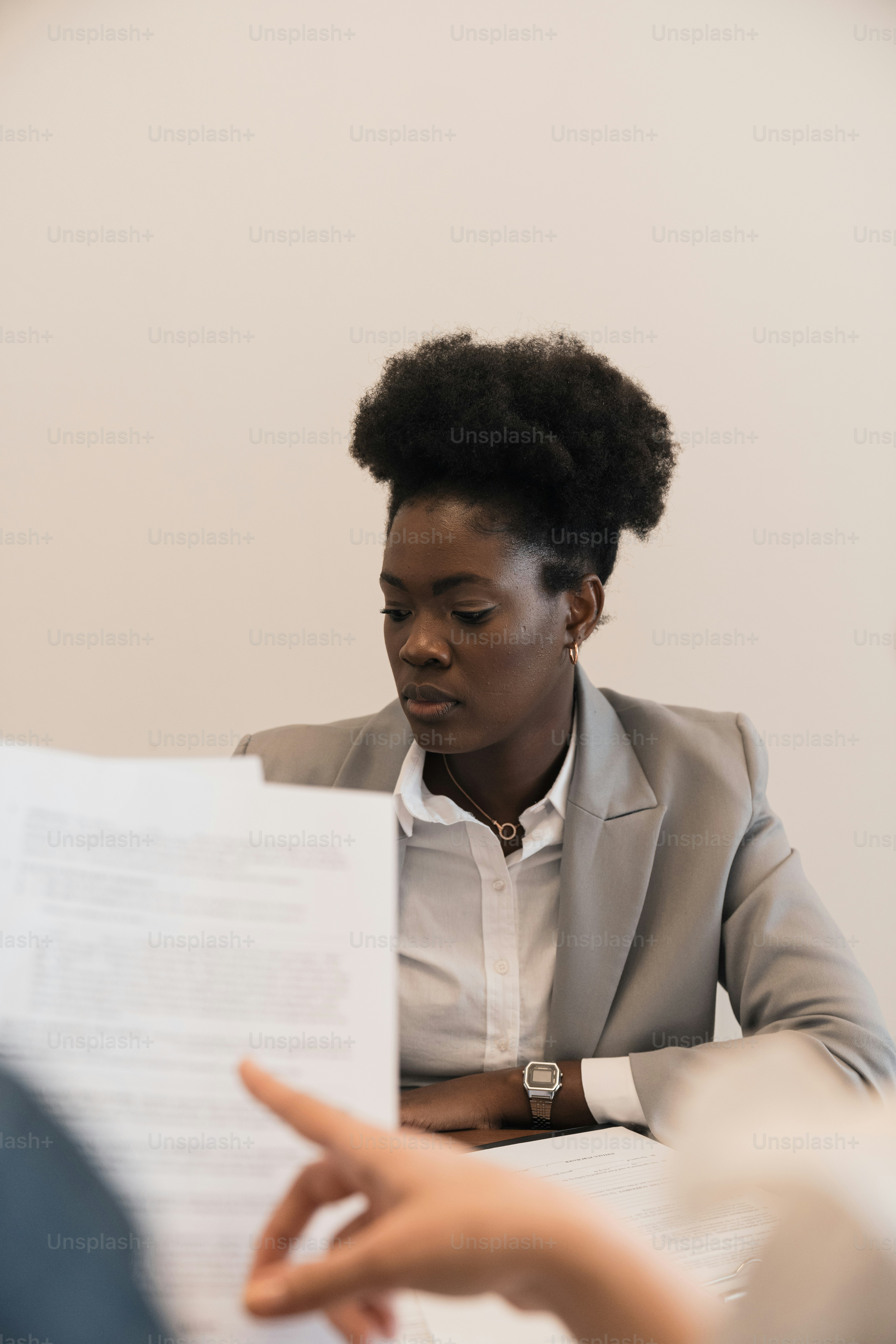a woman sitting at a table reading a piece of paper