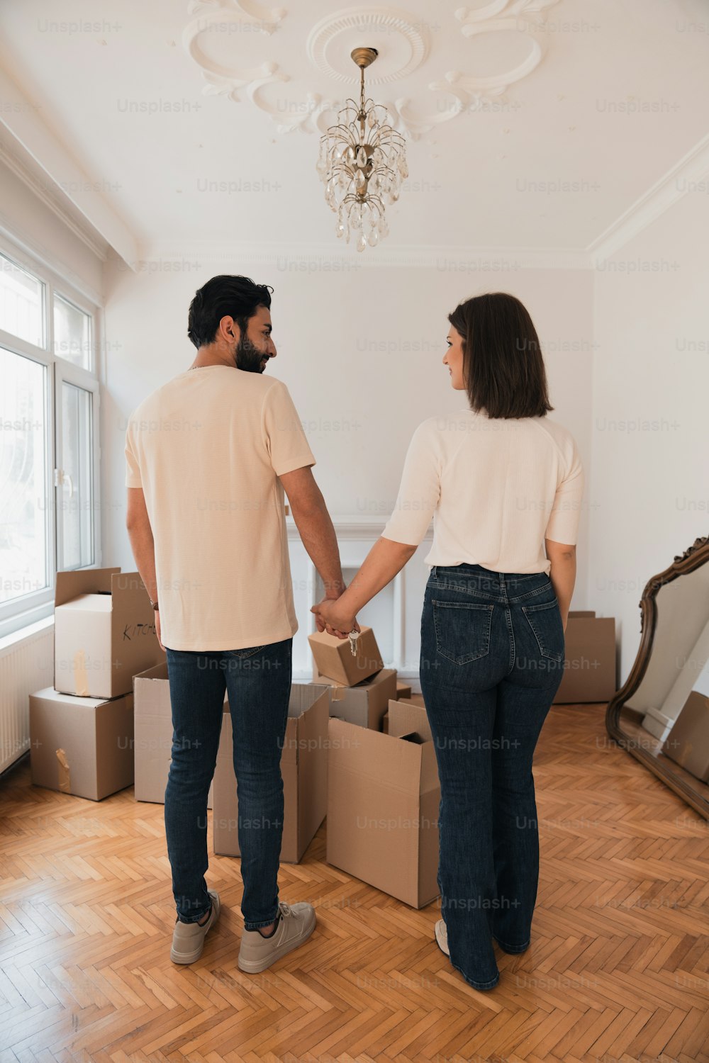 a man and a woman holding hands in a room with boxes