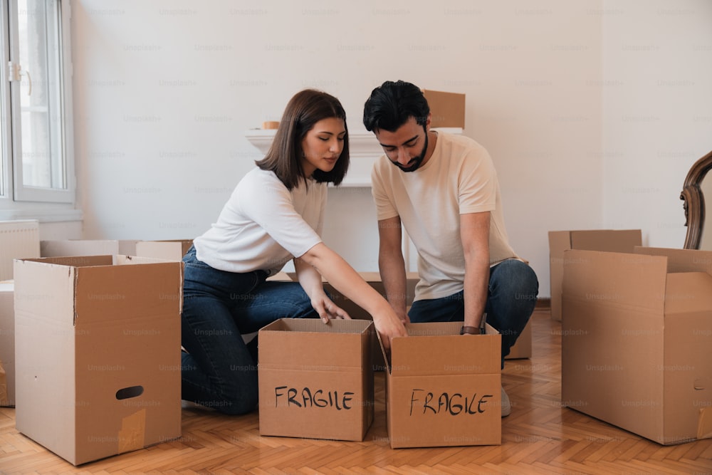 Un hombre y una mujer sentados en el suelo con cajas