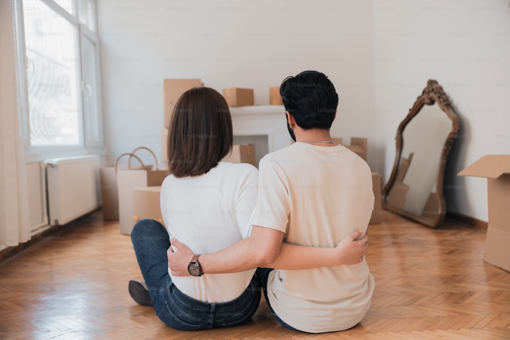 a man and a woman sitting on the floor in front of boxes