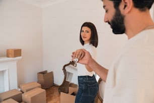 a man and a woman standing in a room with moving boxes