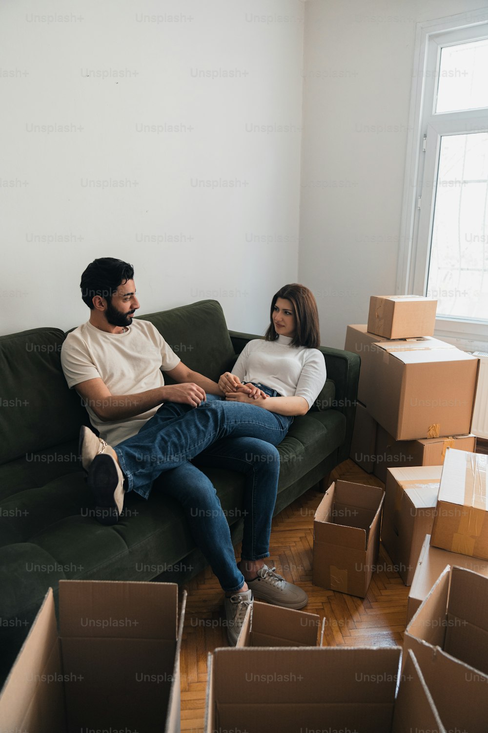 a man and a woman sitting on a couch surrounded by boxes
