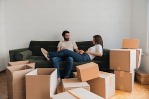 a man and woman sitting on a couch surrounded by boxes