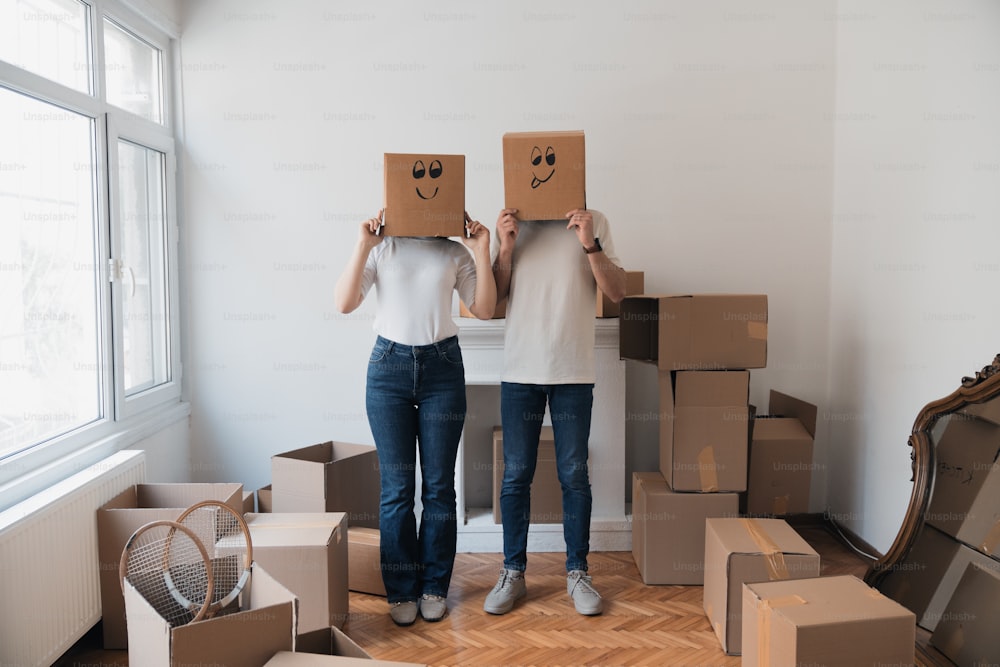 Due persone in piedi in una stanza con scatole in testa