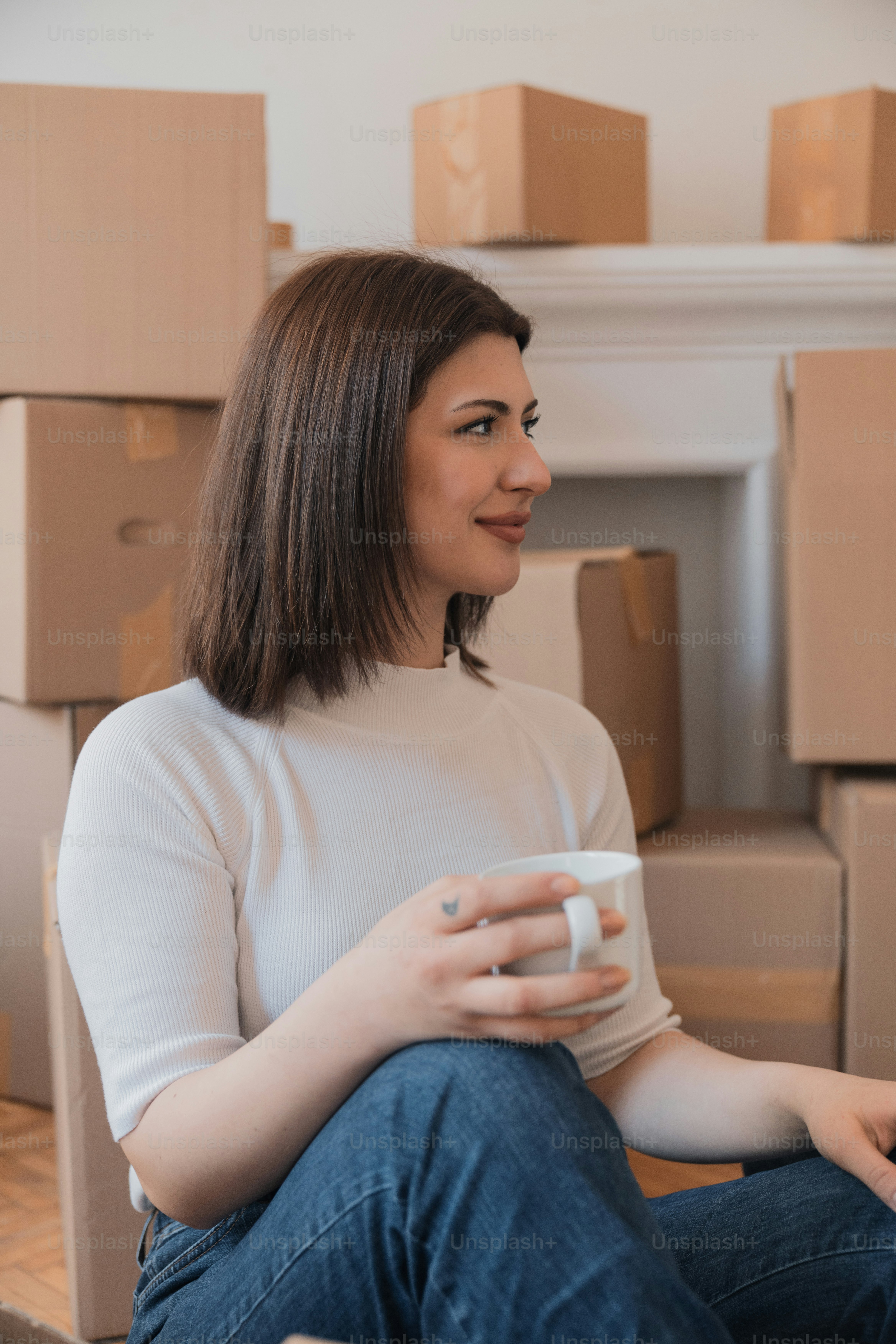 a woman sitting on the floor holding a cup of coffee