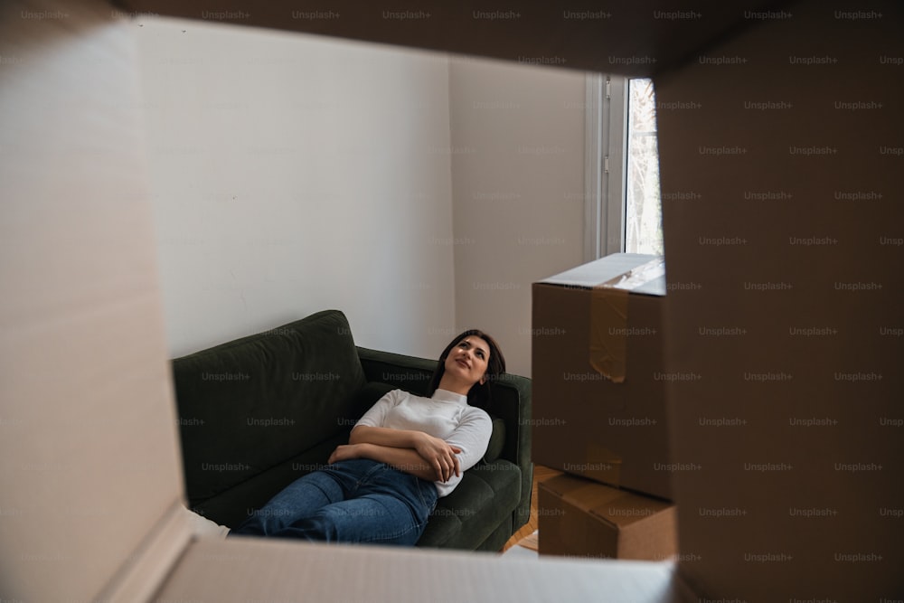 a woman sitting on a couch in a room with boxes