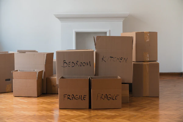 Pile of cardboard boxes on a hardwood floor ready for moving